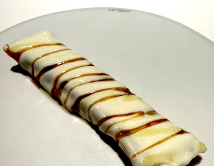 Raviolo di anguilla, cipolla di Breme, olio alla salvia e fonduta di quartirolo lombardo
Più che un raviolo, viene in mente un cannellone, ripieno di anguilla, cipolla di Breme e olio alla salvia, condito con una fonduta di quartirolo lombardo. Il gusto deciso dell’anguilla in stile giapponese è controbilanciato dalla dolcezza della cipolla di Breme, mentre la fonduta di quartirolo apporta la giusta acidità al piatto
