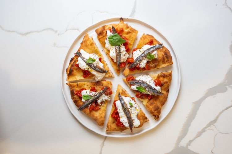 La pizza tonda in doppia cottura in versione Profumo&nbsp;di Amalfi, freschissima, con stracciatella, pomodoro, alici e origano
