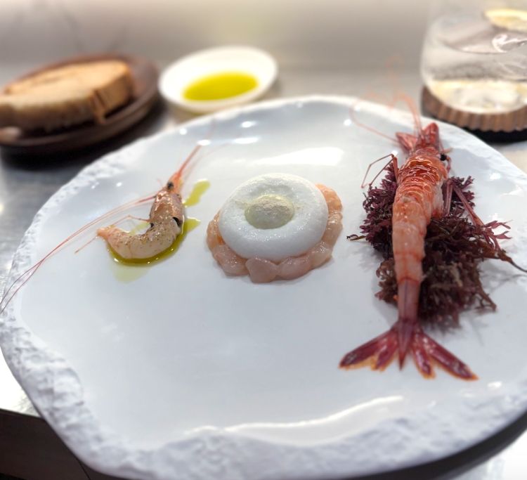 Tartare di gambero bianco, rafano e spuma di latte di pecora, Gambero bianco, olio, sale e pepe e Gambero rosso al naturale. È la volta di un piatto dedicato interamente ai crostacei. Il gambero rosso viene servito crudo, al naturale, per apprezzarne la dolcezza e la purezza aromatica; il bianco compare in due versioni: da una parte intero, proposto con solo olio d’oliva, sale e pepe, e al centro in tartare con rafano e spuma di latte di pecora. Nonostante rafano e latte di pecora siano ingredienti dal carattere deciso, risultano ben dosati e accompagnano il crostaceo senza coprirlo