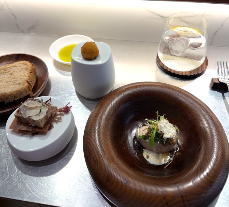 Insalata di fegato di merluzzo, crocchetta di dentice rosso e terrina di cernia. Il primo piatto del menu sartoriale è un tris di assaggi che vedono protagonisti un’insalatina di fegato di merluzzo dal sapore deciso, per poi proseguire con una crocchetta di dentice rosso, mentre si termina con una terrina di cernia profumata da scaglie di tartufo fresco