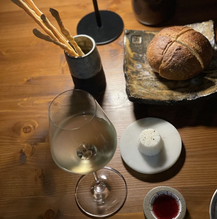 Pane integrale, grissini all'olio d'oliva e farina di polenta, ricottine fatte in casa con siero di latte di capra e pepe nero, e aceto (in cui pucciare il pane) al Montepulciano e more