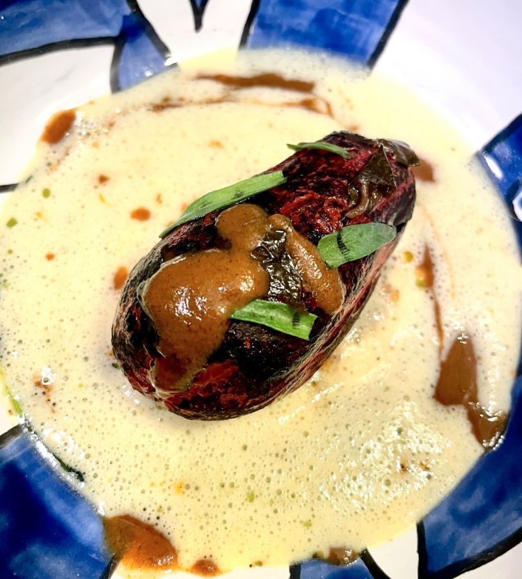 Pomodoro alla brace, meze di mandorla, colatura di tartufo nero e salsa tabarkina
Umami. È la brace, è la leggera fermetazione della mandorla nel meze, è il gusto concentrato della salsa tabarkina (con aceto, peperoncino, pomodoro, capperi e olio), un condimento tipico sardo utilizzato anche in Liguria per condire soprattutto pesce, ma anche verdure; alla base, invece, c'è un brodo di alghe e agrumi che imprimono una freschezza citrica che riporta ordine sul palato​


 
