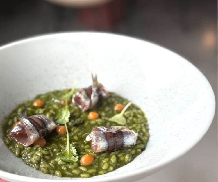 Riso all’aglio orsino, polvere di alghe, alici in carpione e gel di nespole. Il riso è cotto perfettamente al dente. Le alici in carpione e il gel di nespole aggiungono la giusta acidità al piatto. Ed ecco il primo vero azzardo da parte di Alfredo che abbina questo risotto a un Kerner Passito Abbazia di Novacella 2021 da bere solamente una volta terminato il risotto, quasi per pulire la bocca