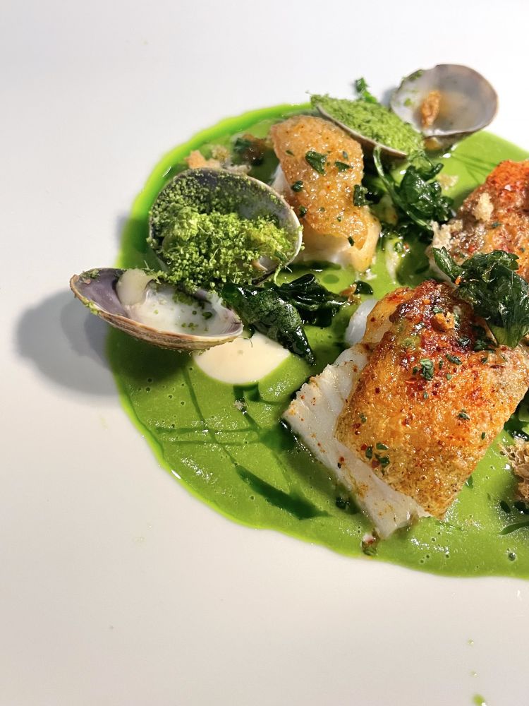 Rombo al verde di Edoardo Tizzanini
Alla base una salsa verde, prezzemolo e tanto mare, quello estratto dagli scarti del rombo che danno all’intingolo profondità; viene variegata da un’aioli, intensa, ma centrata per fissare le sensazioni di mare; quindi vongole gratinate e, protagonista del piatto, un rombo planciato, dalla pelle croccante, come croccanti sono i ciuffi di prezzemolo fritto. Infine, tocchi di peperoncino che apportano una buona dose di freschezza al piatto

