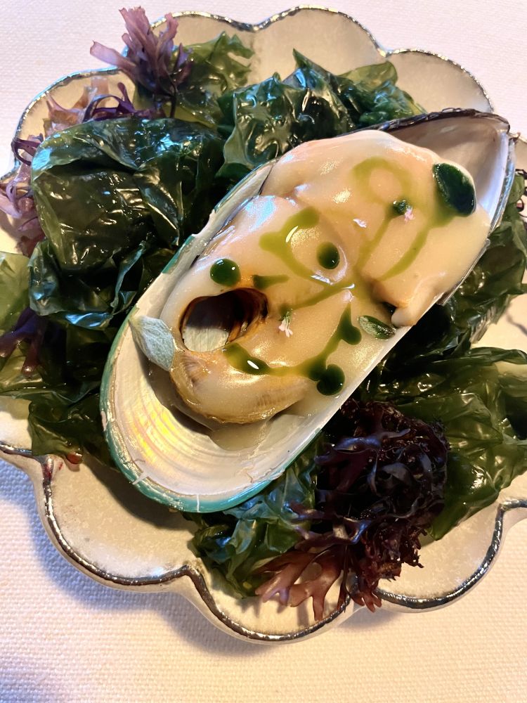 Cozza arreganata
Ischia e il ricordo di un piatto che chef Sodano ama ritrovare lì, sull'isola. Cozze, pan grattato e origano.
Il primo e l'ultimo degli elementi costituiscono uno dei primi bocconi della nostra cena: la cozza viene tagliata in due affinchè possa essere gustata con tutti gli elementi che la completano. Mare ed erba aromatica si alternano in una gara di lunghezze iniziando l'ospite a quel viaggio continuo tra iodio e orto