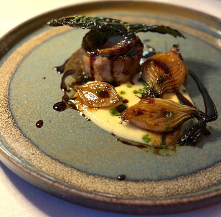 Roll di coniglio nostrano, purea di patate e lavanda, salsa ai funghi shiitake e coniglio, cipollotto al grill. Il coniglio rimane tenero e saporito; la purea di patate, con un tocco di profumata lavanda, è setosa e delicata, i cipollotti sono dolci, mentre la salsa ai funghi shiitake e coniglio è decisa e intensa. Un altro piatto gustoso e armonioso in cui tutti gli elementi si sposano alla perfezione. Rimaniamo in Toscana con il vino e proviamo un calice di Sangiovese Sacromonte Castello di Potentino 2019.