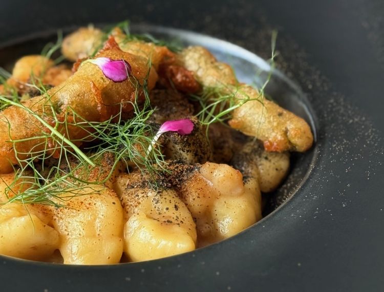Gnocchi di patate e katsuobushi, bisque di crostacei, gamberi, asparagi in tempura e polvere di riccio di mare. Gli gnocchi sono fatti in casa e vengono serviti con una tempura di asparagi che apporta croccantezza, mentre i ricci di mare e il katsuobushi (tonno essiccato) aggiungono sapidità e un sapore deciso di mare; i gamberi, in ultimo, donano dolcezza al piatto ben bilanciato. In questo caso ci viene proposto un Bolgheri Rosato 3 File Pietra Nova 2024.