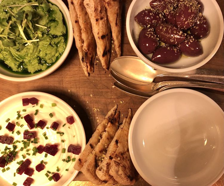 La classica pita servita con due salse in accompagnamento: la prima, in basso a sinistra a base di yogurt, uova di merluzzo, barbabietola ed erba cipollina e, in alto a sinistra, una crema poco raffinata con prezzemolo, aglio e patate; olive kalamata condite