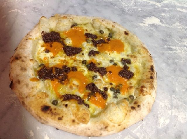 Pizza SorridiAfrica, created by Pepe: the topping recalls the colours of that continent, with olive pâté, capers, cream of pepper, dried tomatoes and cheese from Matese