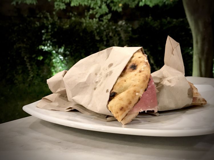 La pitta di Franco Pepe, una novità studiata durante il delivery perché si può mangiare anche fredda, o il giorno dopo. Qui è condita con prosciutto crudo San Daniele, olio alle erbe, confettura di fichi bianchi del Cilento, menta, basilico e formaggio Fabula, un crosta fiorita di bufala del caseificio Il Casolare di Avigliano. L'insieme è buonissimo
