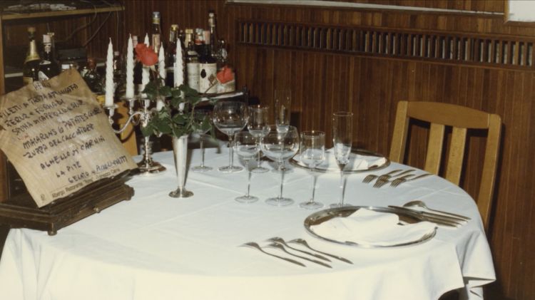 Un tavolo con menu dell'Albergo Roma al tempo di Cosetti. Le portate: Filetti di trota affumicata, Peruz e formadi (formaggi con le pere), Spuma di capriolo e olive, Macarons & patates crudes, Zuppa del cacciatore, Agnello di Carnia, La pite, Gelato ai piccoli frutti