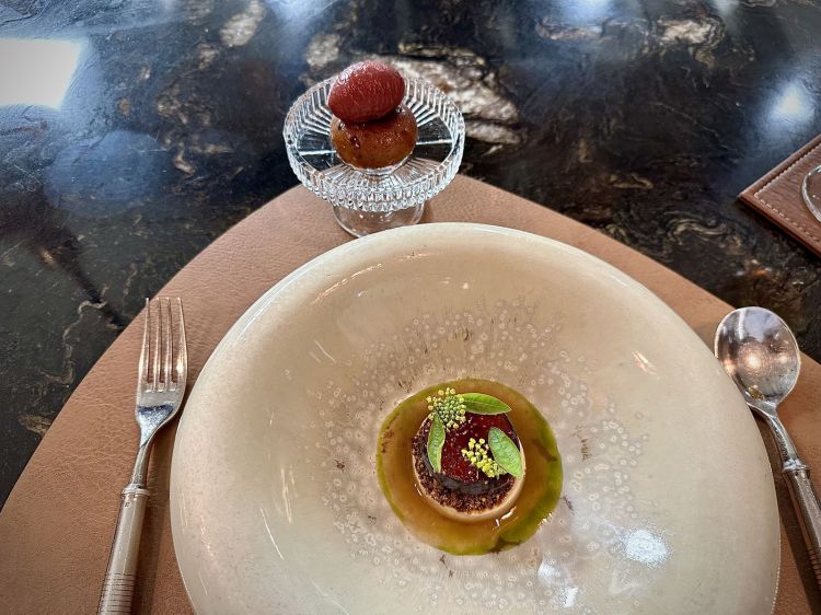 Flan de leche in infusione di foglie di fico: esse ricordano il caffè, perché vengono usate essiccate, e sono utilizzate per questo flan suadente e cremoso, impreziosito da un mix spezie satay, fico macerato (in aceto di riso, acqua e zucchero), infusione di foglie di more, foglie di cassis, camomilla e altre erbe. A lato, un Babà ai fichi e caffè e un sorbetto 100% fichi senza zuccheri aggiunti. Golosità più comfort, ma mai banale
