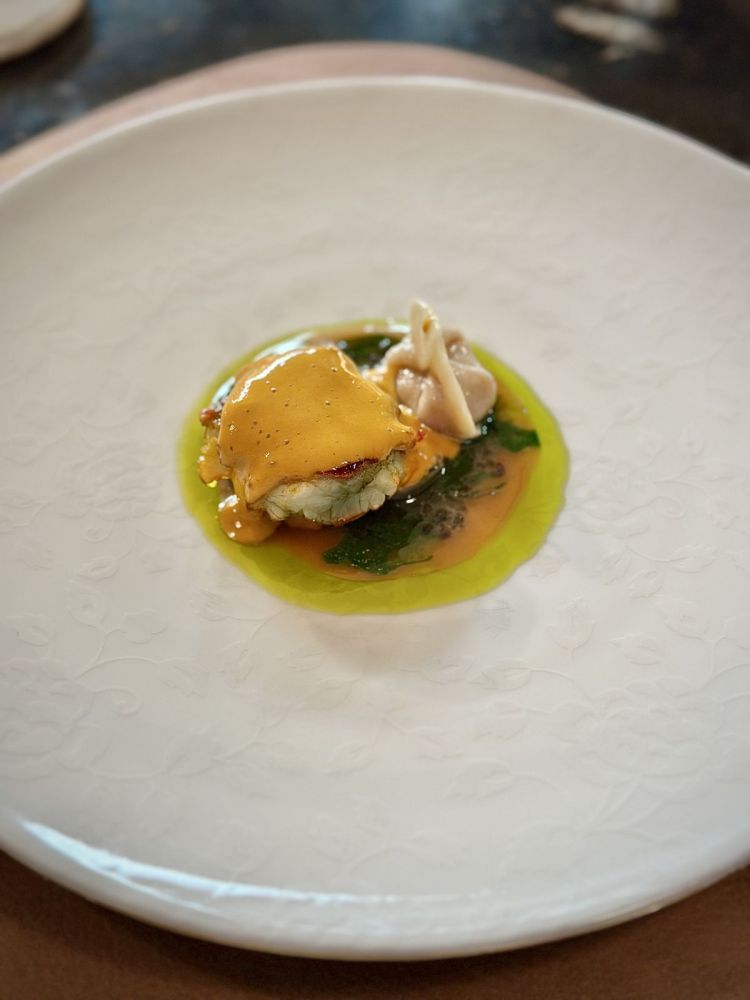 Astice blu bretone, uva Chasselas, insalata di lenticchie, sedano, prezzemolo, raviolo di chele di astice, bisque di astice e foglia di fico
