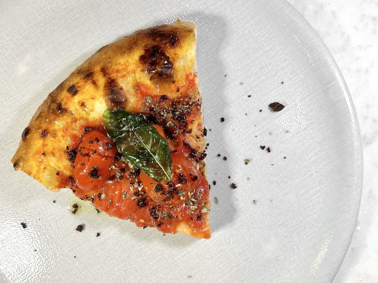 L’impasto di Franco Pepe sotto un ulteriore punto di vista, ossia in teglia, quindi a temperatura più bassa rispetto alla classica in pala: ecco La Ritrovata, dedicata al padre di Franco, Stefano. Alla base pomodori san marzano e piennolo, poi polvere di olive caiazzane disdratate, filetti di alici di Cetara, olio evo agliato, origano del Matese e basilico cristalizzato