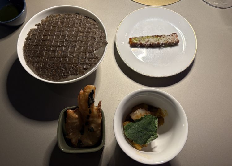 I quattro assaggi con cui si &egrave; aperta la cena.&nbsp;Iniziando dall'alto, a sinistra, e procedendo in senso orario: Cialda di seppia, bietola in zimino, maionese di limone salato e salsa verde di erbe spontanee&nbsp;- Tortino di datterino con estratto di abete bianco e parmigiano - Cardi, datterino giallo, mazzancolle e mostarda di clementine e pomodoro - Finocchio lesso, passato in&nbsp;una pastella di chinotto, caviale di aringa e burro di pinoli&nbsp;
