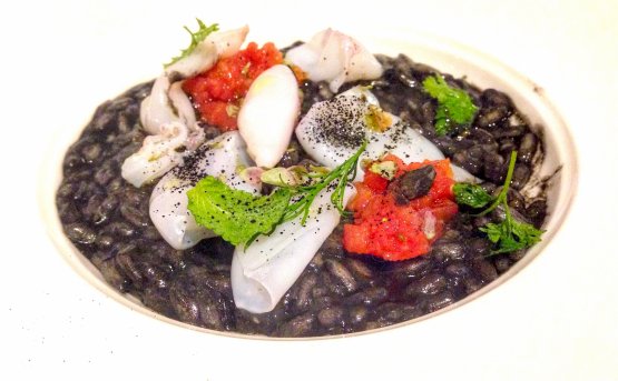 Il Risotto Carnaroli all'olio Nocellara con calamaretti spillo al nero, capperi di Pantelleria e profumo di limoni della Costiera di Negrini-Pisani
