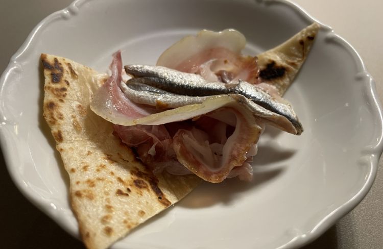 Il benvenuto dalla cucina è un simbolo del rapporto di Da Lucio con la Romagna: Piada sfogliata, pancetta e alici
