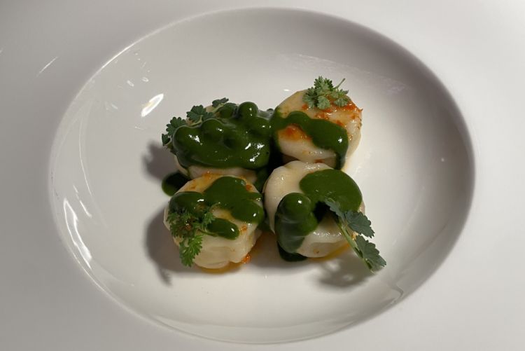 Raviolo d’ostrica
«Il piatto è ispirato da un viaggio fatto in Cina, dove mi sono innamorato dei ravioli della tradizione cinese. Ho voluto realizzarli con un ripieno cremoso di ostrica: come prima cosa usiamo la proteina dell'ostrica per ottenere un'emulsione, poi aggiungiamo dei pezzetti di ostrica per dare consistenza, e chiudiamo il ripieno con una pasta simile a quella che si usa in Cina. I ravioli vengono cotti a vapore e poi glassati in padella con grasso d'anatra affumicato e un battuto di peperoncino, zenzero, aglio. Li serviamo con una salsa al dragoncello e delle piccole sfere di cetriolo, che danno un po' di acquosità e freschezza»