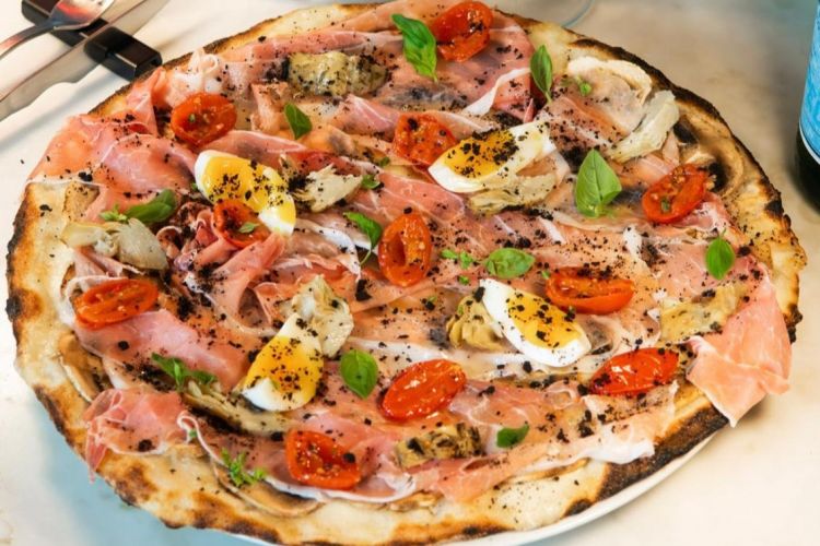 Capricciosissima: pomodoro datterino semi dry, prosciutto crudo 24 mesi, treccia di fiordilatte, funghi, carciofi arrosto, polvere di olive, uovo barzotto
