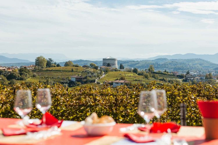 Bicchieri di Ribolla d'Oslavia, il territorio con le colline, i vigneti e, sullo sfondo, in località Ossario, il Sacrario militare che custodisce le spoglie di quasi sessantamila soldati (540 dei quali austro-ungarici): una sintesi della storia, e di questa storia
