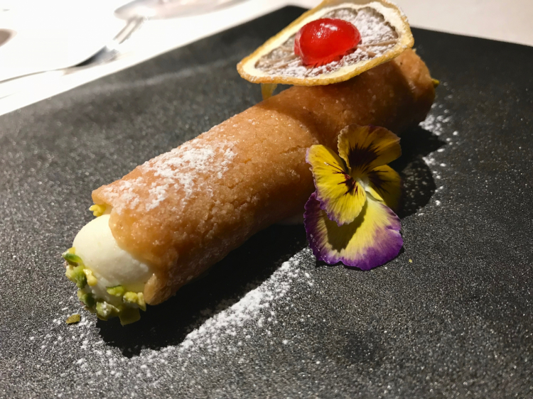Cannolino vestito di nuovo: cialda di torroncino di nocciole, cotto al forno, ripieno di ricotta con agrumi e frutta candita. Goloso finale