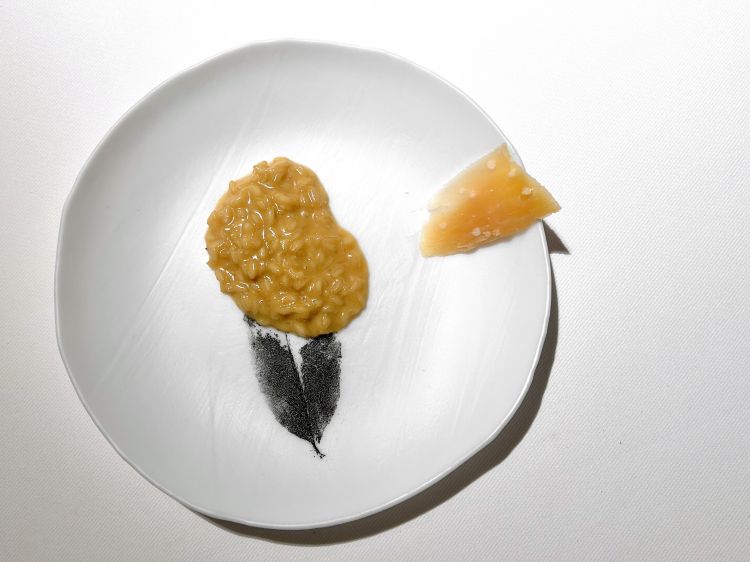 Terzo capitolo: la foresta. La solita slavina di snack: Bagel di Parmigiano e tendini; Falsa pelle di anatra alle mele (una demi glace di anatra, molto gelatinosa, spennelleta sulle foglie di ovulato, che sono poi seccate e fritte. È l'idea di rileggere un piatto della tradizione polacca, l'Anatra alle mele, con due purè, uno scuro di mela bruciata, l'altro chiaro di mela cotta nel grasso di anatra), quindi Lingua alla vinaigrette, Cuore di pollo (marinato e alla griglia) con ketchup di lamponi. Poi, nella foto, Groseran, un risotto. «Prima proponevo un risotto al brodo di prosciutto. Ora ho conosciuto il groseran, un formaggio locale, di capra, lo chiamano "parmigiano polacco". Viene stagionato un anno e mezzo su assi di faggio, acquista così profumi di sottoboosco, di liquirizia, di porcini». Il sapore è intenso, Arcieri vi manteca il riso, con brodo di pollo e olio evo