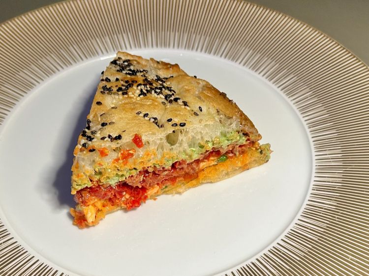 Wheely Margherita (impasto cotto al padellino e aromatizzato al pomodoro e sesamo bianco, farcitura di treccia di bufala, tartare di pomodoro arrosto, insalatina di basilico, crema di pomodoro secco Casa Marrazzo e maionese al basilico)