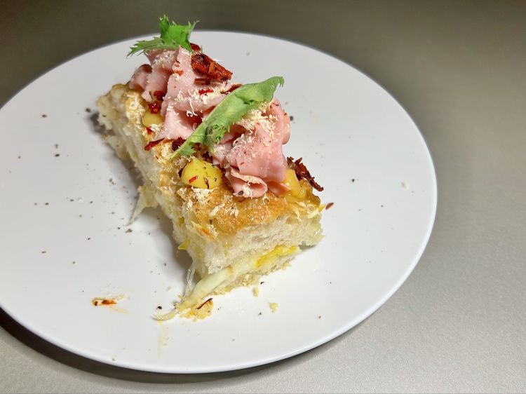 Focaccia Emilia-Lucania (impasto di focaccia farcito con mortadella, fiordilatte di Napoli Latteria Sorrentina e pomodorino giallo Casa Marrazzo, guarnito con ketchup di pomodorino giallo, ricottina piccante, peperone crusco e mizuna corallo