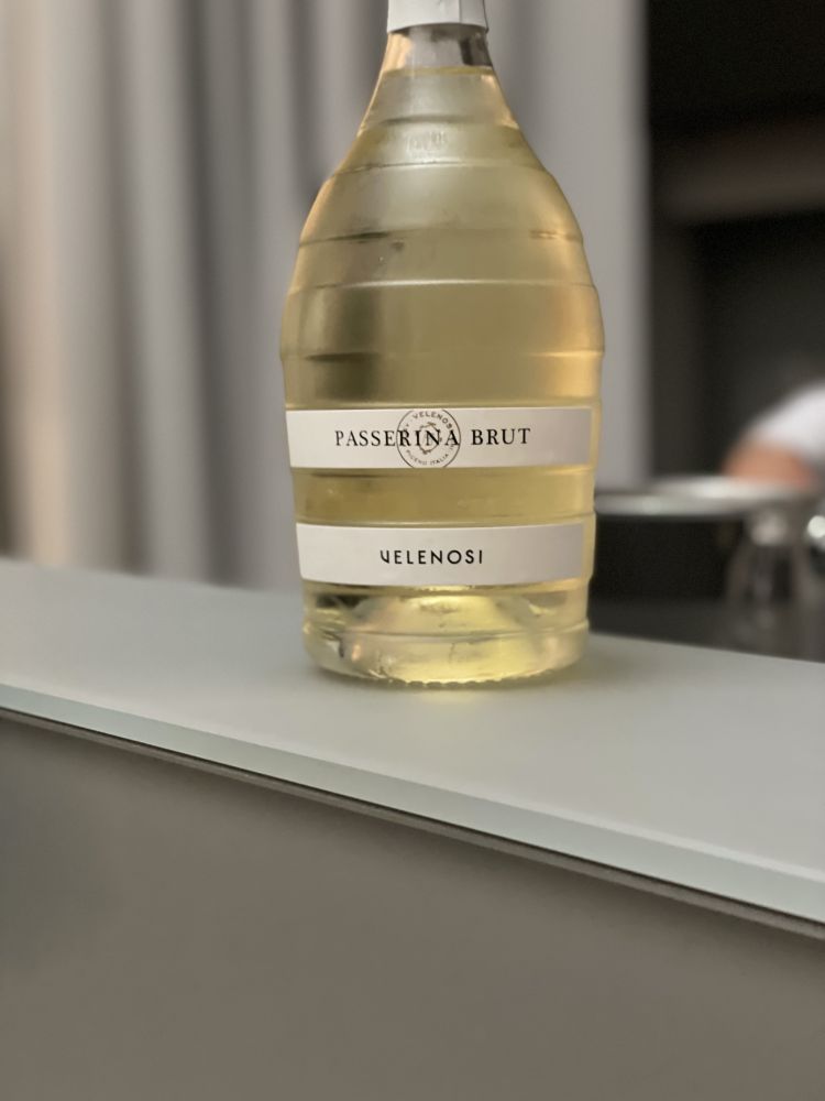 Cosa si beveva al Clandestino 20 anni fa all'ora dell'aperitivo? Il Passerina Charmat di Velenosi Vini, che ritroviamo all'hub come calice di benvenuto per brindare ai successi di Moreno e Mariella. Passerina al 100% da vigneti di proprietà della cantina Velenosi situati ad Ascoli Piceno. Dopo una breve criomacerazione delle uve e la pressatura soffice, la fermentazione è avviata e termocontrollata in acciaio inox. Terminata la prima fermentazione, il vino base viene predisposto per rifermentare in autoclave con la presa di spuma.
Ci troviamo davanti a un vino dal giallo luminoso con riflessi argentati; presenta un perlage fine e persistente. Al naso, intense nuance di frutta bianca e cedro con finissime note floreali e fragranti del fiore d'acacia. Sul palato freschezza e sapidità in grande evidenza; vivaci sensazioni agrumate contrastate da un'inaspettata morbidezza.
