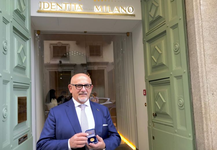 Claudio Sadler mostra la medaglia d'oro ricevuta dal Comune di Milano davanti all'entrata di Identità Golose Milano
