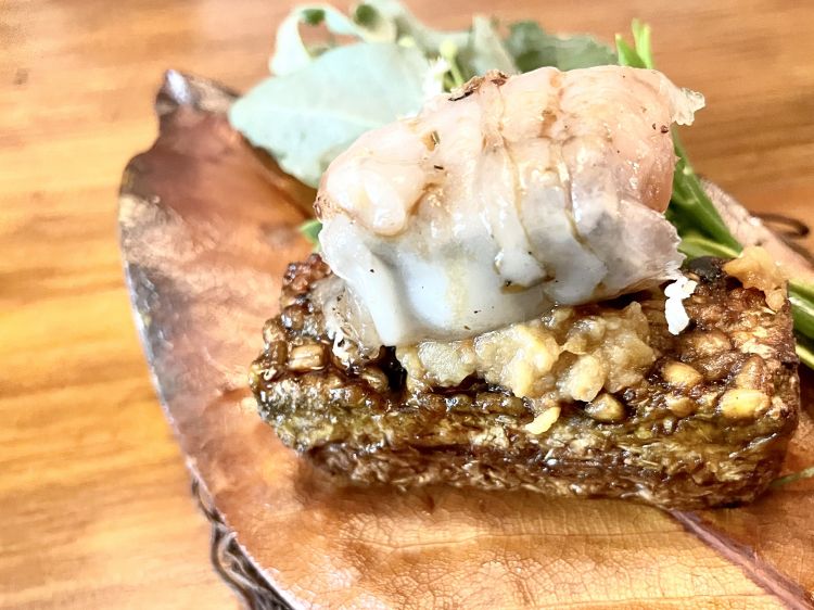 Koji e pesce gatto
Un “tortino” di koji, maltato, l’impasto è vicino a una segale molto concentrata, asciutta, dall’acidità pungente; assorbe tutta la succosità, in cima, del pesce gatto lardellato, grasso; un boccone rinfrescato sul finale da senape selvatica