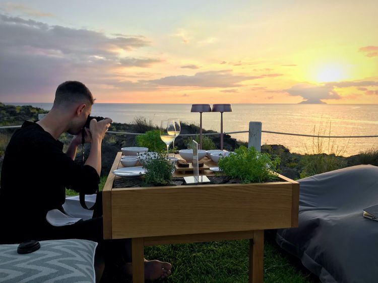 Our Tanio Liotta prepares the space for the photos, on the tables at I Tenerumi. In front of him, a beautiful view