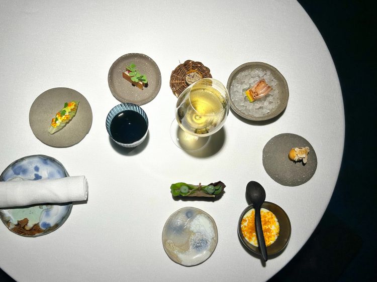 Giro di appetizer: Sandwich di mela, tartare di palamita, maionese alle alghe; Uovo di quaglia marinato in brodo di tonno, spuma di patate e bottarga di muggine; Speck di pesce spada affumicato e melone, rivisitazione di prosciutto e melone; Krapfen ai funghi con carpaccio di funghi, polvere di funghi e tuorlo marinato; Tartelletta alle cipolle, paté di rana pescatrice, tartufo nero; Wafer di patate, baccalà mantecato e gel di cipolla, Foglia di lattuga, hummus di pistacchio e caviale di trota salmonata. Krapfen e tartelletta abbinano gioiosamente note di terra, di bosco, a quelle umami o salmastre
