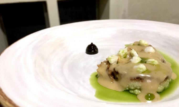 Cavolfiore, aglio fermentato. L'ortaggio è cotto in padella con fieno e burro, poi vinaigrette al rafano, aglio nero, olio di erba cipollina, salsa di verdura concentrata, come fosse un fondo. In effetti il piatto vuole ricordare un arrosto di carne. Il punto forte è la texture e la piccantezza