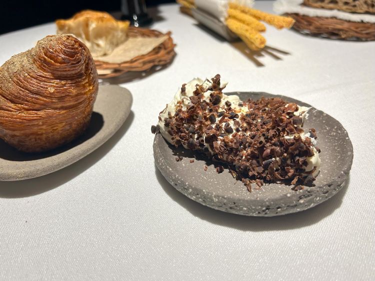 Burro al fieno (una novità): burro montato, affumicato al fieno, emulsionato e condito con cuore di tonno essiccato homemade e poi grattugiato. Pane all’orzo, grissini alla polenta, focaccina di patate e pane sfogliato al pomodoro con polvere di capperi
