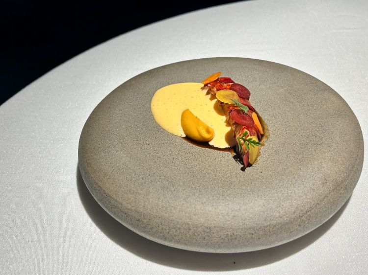 Astice blu, carota: cotto alla brace e laccato con succo di carote tostate, crema di carote, diverse consistenze di carote gialle, arancioni e rosse, zabaione al Marsala. A fianco, con la testa dell’astice viene preparato un consommé stile bisque con aggiunta di agrumi e carote. La parte esterna della carota è fritta passata alla brace e farcita con insalata di carote e chele di astice