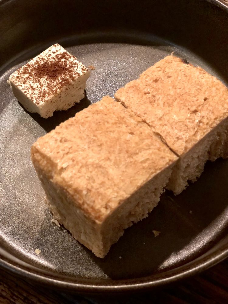 Il pane del panificio meneghino più piccolo d'Europa, ovvero il micropanificio artigianale TraMa di Matteo Trapasso - un impasto lavorato con lievito madre, farro, farina integrale di tipo 2 e segale. Viene accompagnato da burro aromatizzato al lievito di birra fermentato e cacao
