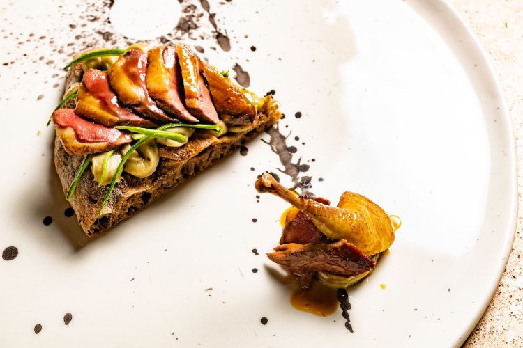 L'ormai celeberrima pizza Piccione al forno, con fiordilatte, petto di piccione al forno a legna, fagiolini neri, coscia confit e fondo al campari