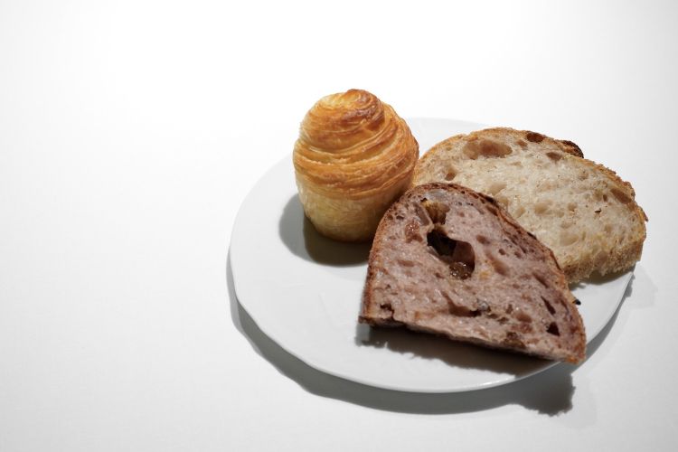 Tre tipi di pane, ciascuno elaborato a rappresentare un fratello Roca diverso: pane classico di Joan, pane con impasto di vino rosso e uva passa di Josep, pane sfogliato con pomodoro di Jordi
