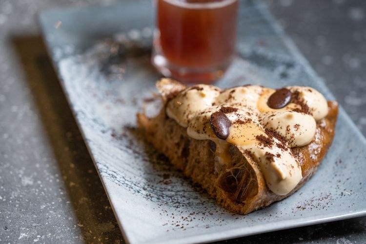 L’insolito dolce: impasto al caffè cotto a vapore a 130 gradi. Topping di ganache al caramello e mousse al caffè. È accompagnata da una birra artigianale al caffè del Birrificio dell’Etna
