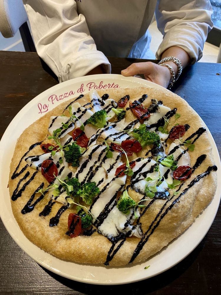 La pizza fritta che celebra il baccalà: Nero a Metà con baccalà in olio cottura, datterino secco, cime di rapa e latte cotto al nero di seppia
