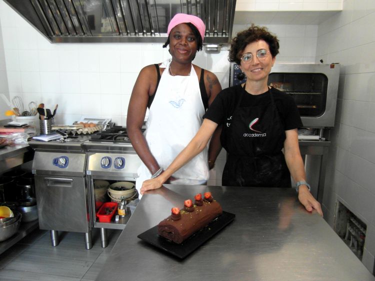 La nigeriana Bridget e la pasticcera Mara sorridono con l'ultima creazione per il ristorante Moltivolti