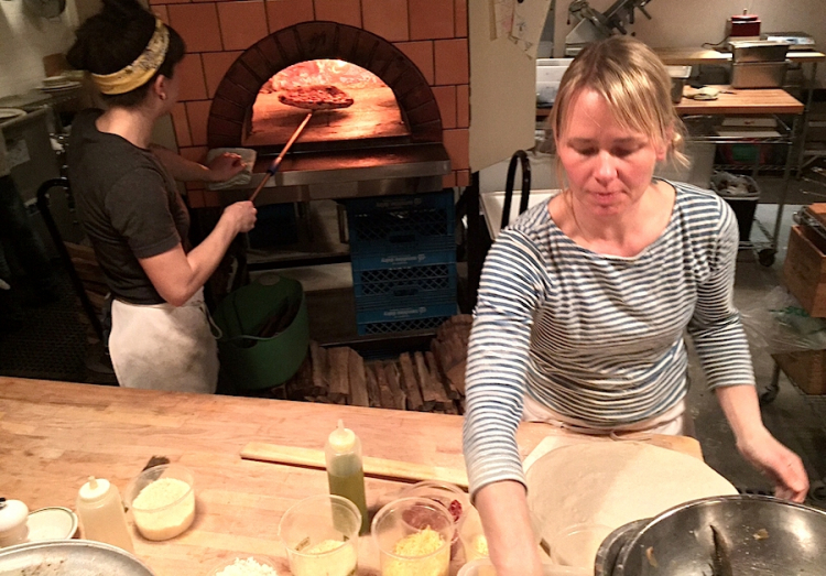 Mentre Sarah Minnick prepara una pizza, Emily Sguadra ne cuoce una nel forno
