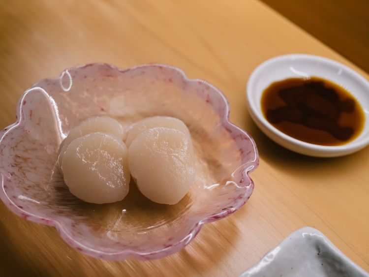 La capasanta di Moi Omakase arriva dalla prefettura di Hokkaido, la più fredda in assoluto in Giappone. La sua particolarità? Nascendo in un habitat dal clima particolarmente rigido, non riesce a sviluppare massa muscolare; di conseguenza non ci sarà masticazione, si scioglierà completamente in bocca. Viene servita con salsa di soia