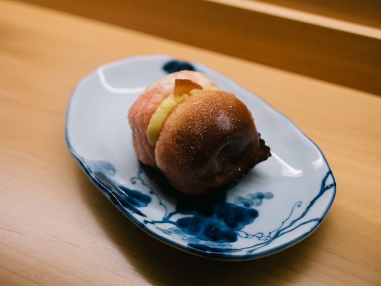 La Pesca di Prato, una specialità della Pasticceria Nuovo Mondo a Prato: due piccole brioche ripassate nello zucchero semolato e unite da uno strato generoso di crema pasticcera, immerse il giusto in una bagna a base di alchermes
