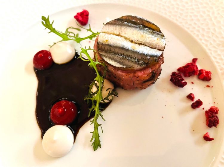 Rollé of leg and saddle of lamb with a disc of marinated anchovies, anchovy emulsion and raspberries, served with its jus
