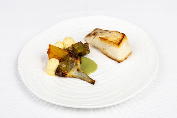 Trancio di pescato alla brace, in questo caso morone, accompagnato da carciofi, patate e menta