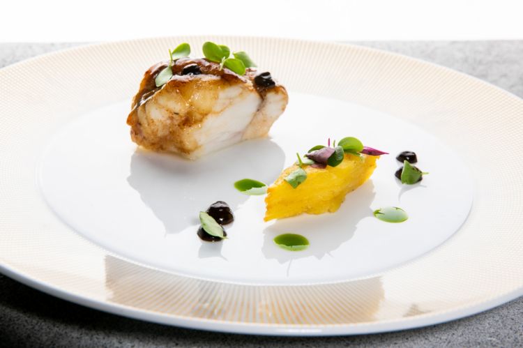 Pescatrice millefoglie di patate e aglio rosso del Fucino fermentato
«Anche la pescatrice l'ho scelta perché per noi in Adriatico è uno dei pesci più apprezzati e utilizzati, sia nelle grigliate che al forno. Poi ho deciso di usare questo aglio particolare, che mi ha proposto un produttore abruzzese per farlo conoscere. Oggi l'aglio nero lo troviamo in molte cucine anche in Italia, e mi piace molto poter usare un aglio rosso fermentato che nasce in Abruzzo. Conferisce una nota leggermente rustica, classica dell'aglio, ma delicata, equilibrata, ottima per accompagnare la pescatrice che viene cucinata alla brace»