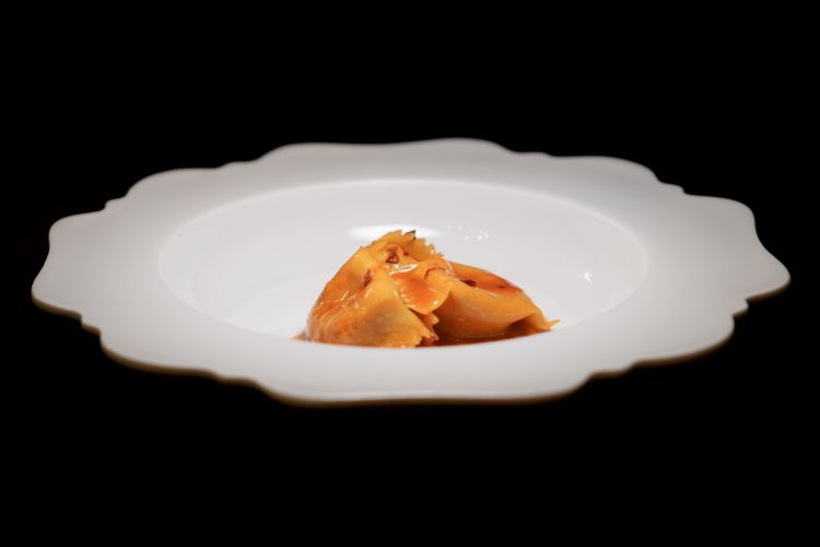Plin ripieni di caprino e mostarda di albicocche con estrazione di peperone rosso e crusco: Antonio Romano lavorava prima a Torino, questo piatto richiama la sua esperienza in Piemonte. &Egrave; un raviolo del plin ripieno di formaggio caprino locale, completato con mostarda di albicocca. Viene risottato in una crioestrazione di peperone rosso, infine peperone crusco croccante
