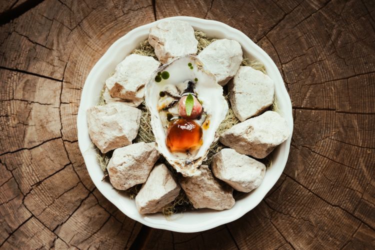 Dopo gli appetizer (Arlette salata con misto di insalate fresche ed erbe di montagna, pecorino grattugiato e lardo; Fico impanato e fritto con salsa shichimi tōgarashi (“Peperoncino ai sette sapori”); Gazpacho di fragole alla brace, pomodoro alla brace e peperone rosso, olio alla menta) il primo piatto del nostro percorso è Ostrica alla brace, ormai una proposta signature: ostrica cotta alla brace e affumicata, lardo, gel di ponzu